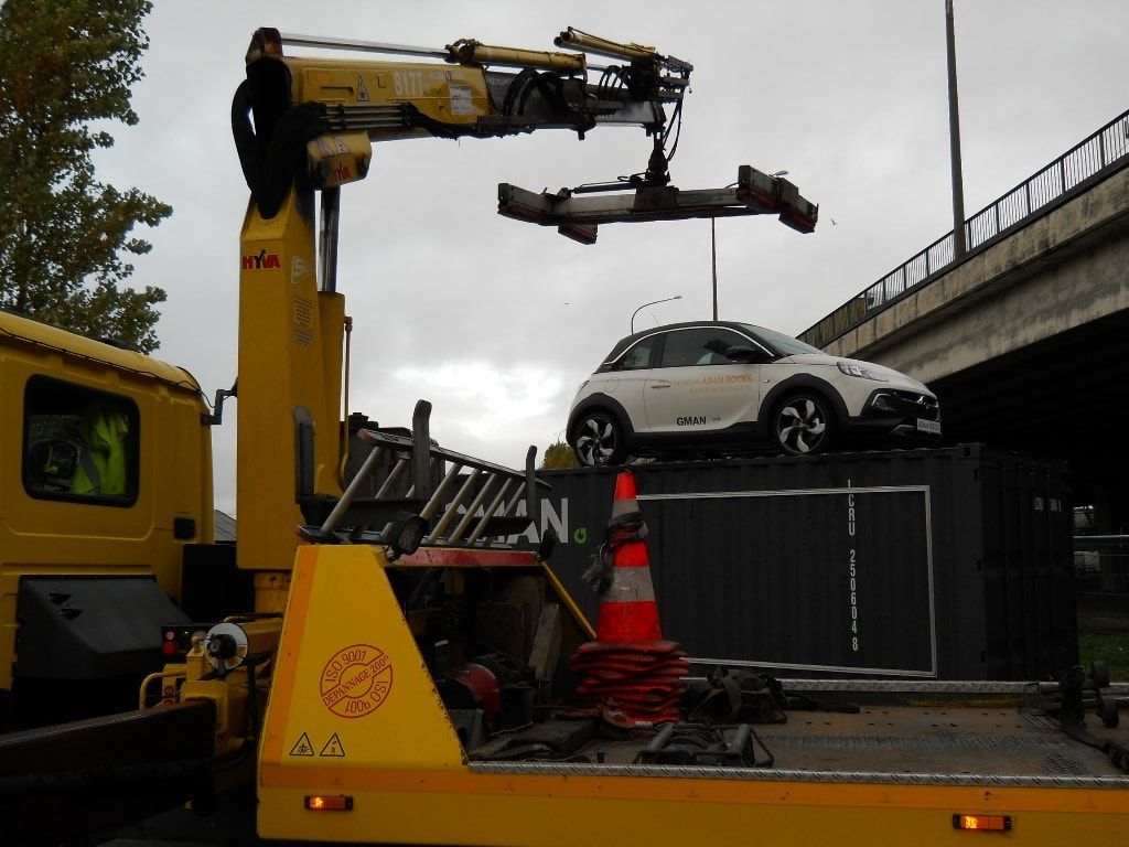 Kraanwerk waarbij een voertuig op een container wordt geplaatst