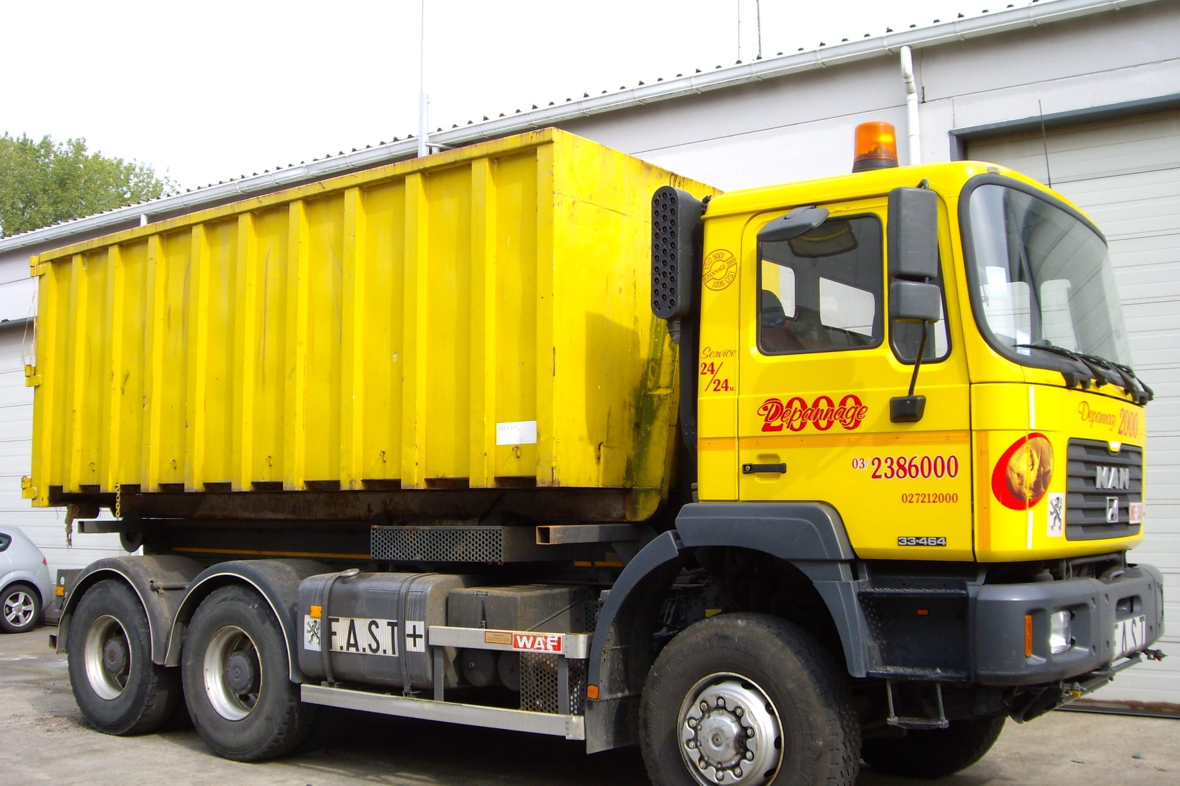 Gele MAN-containerwagen met afzetcontainer