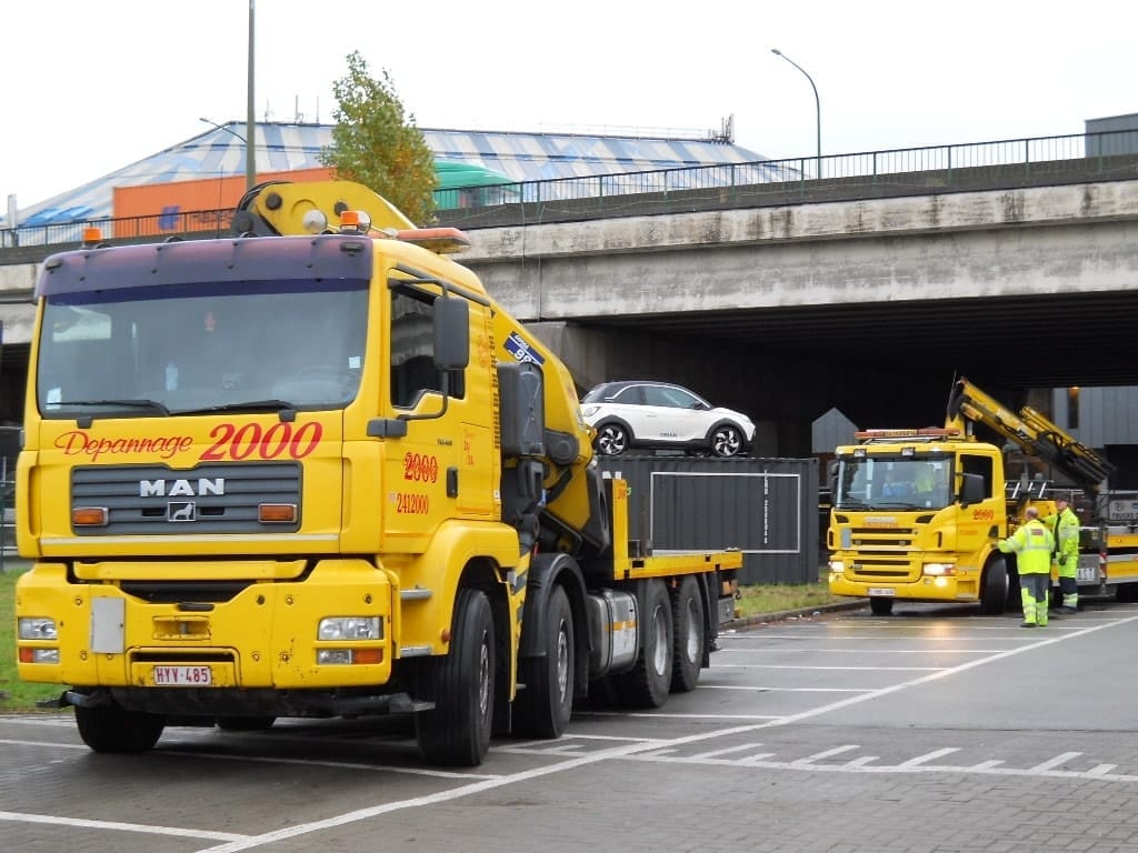 Een voertuig wordt met een kraanwagen op een container geplaatst